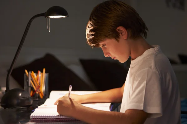 Menino jovem estudando na mesa no quarto — Fotografia de Stock