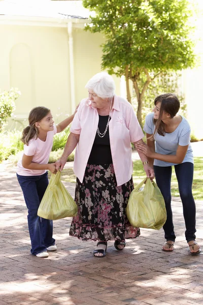 Grandchildren Helping Grandmother To Carry Shopping — Stockfoto