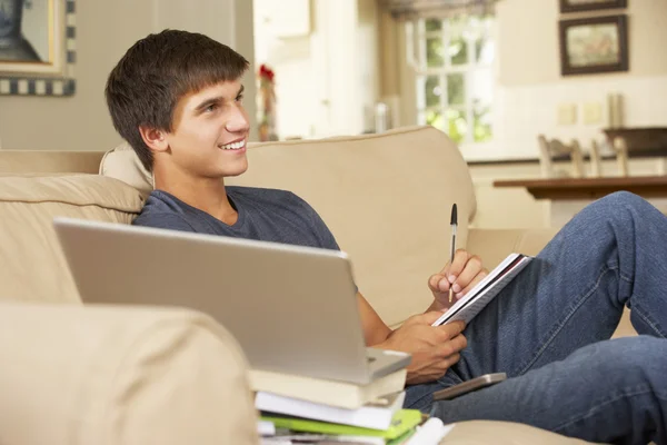Junge macht Hausaufgaben, während er fernsieht — Stockfoto