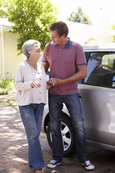 Mann hilft Seniorin ins Auto — Stockfoto
