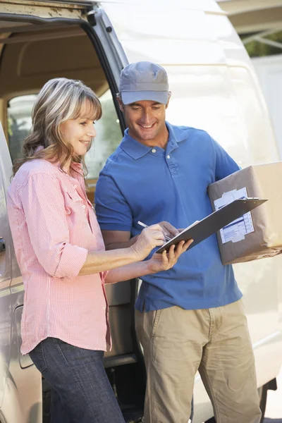 Woman Signing For Packager Delivered By Courier — Stockfoto