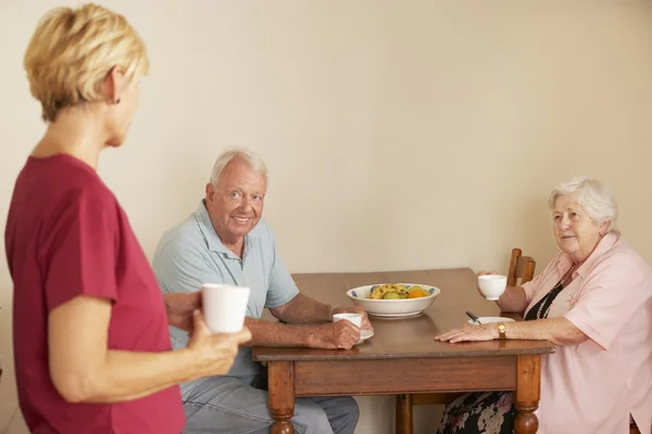 Ayudante de casa con pareja mayor en la cocina — Foto de Stock