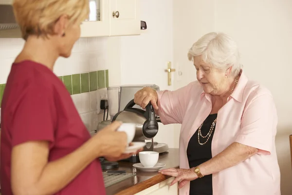 Ayudante de casa con la mujer mayor en la cocina — Foto de Stock