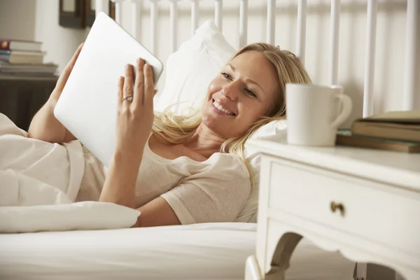 Γυναίκα χρησιμοποιώντας ψηφιακή δισκίο στο κρεβάτι — Φωτογραφία Αρχείου