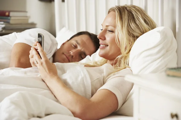 Vrouw met mobiele telefoon in bed — Stockfoto