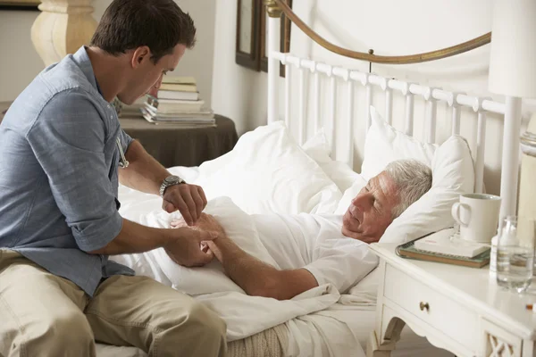 Doctor tomando el pulso de un paciente masculino mayor — Foto de Stock