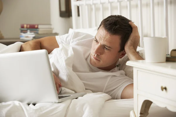 Człowiek korzysta z laptopa w łóżku — Zdjęcie stockowe