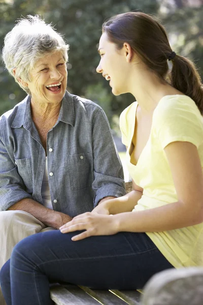 Grandmother Talking With Teenage Granddaughter On Bench — ストック写真