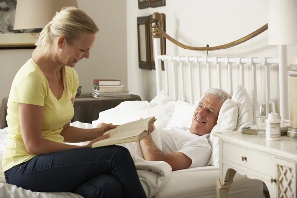 Volwassen dochter lezing naar Senior ouder — Stockfoto