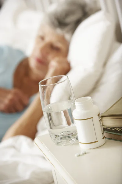 Medicatie op het nachtkastje van slapende vrouw — Stockfoto