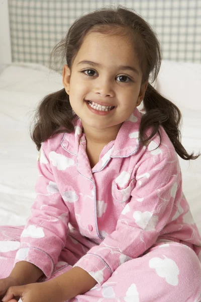 Yatağın üstüne oturan pijama giymiş kız — Stok fotoğraf