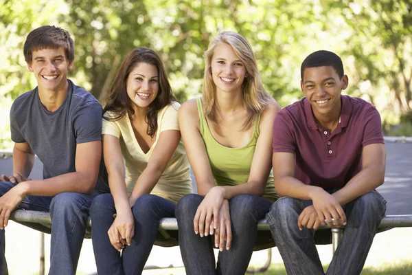 Amis adolescents assis sur le trampoline dans le jardin Images De Stock Libres De Droits