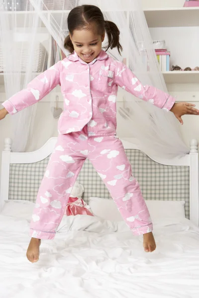 Rapariga em pijama pulando na cama — Fotografia de Stock