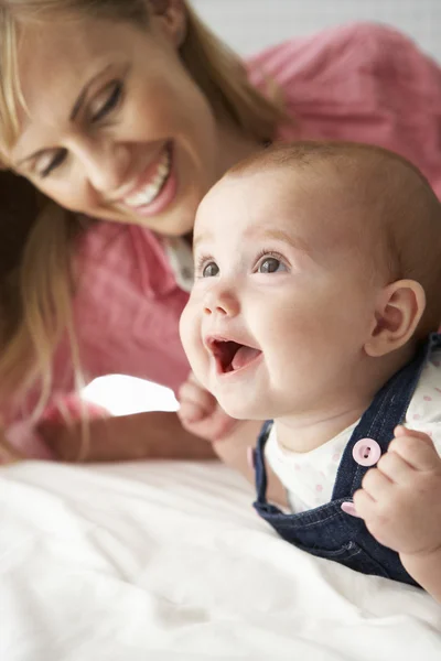 Anne ile bebek kız yatakta oynamaktan — Stok fotoğraf