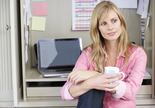 Женщина пьет кофе в домашнем офисе — стоковое фото