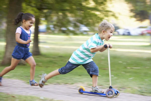 男孩在公园与姐姐在滑板车上 — 图库照片
