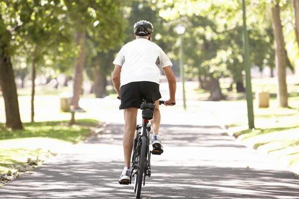 Maturo uomo ciclismo attraverso parco — Foto Stock