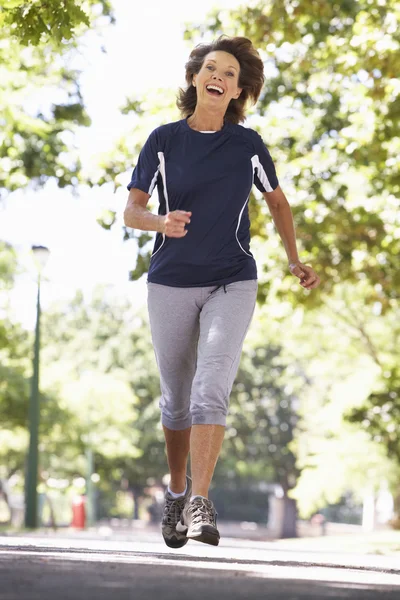 Femme âgée courant à travers le parc — Photo