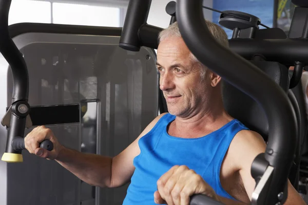 Hombre usando la máquina de pesos en el gimnasio — Foto de Stock