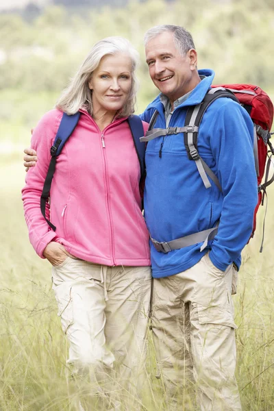 Casal sênior em caminhada pelo campo — Fotografia de Stock