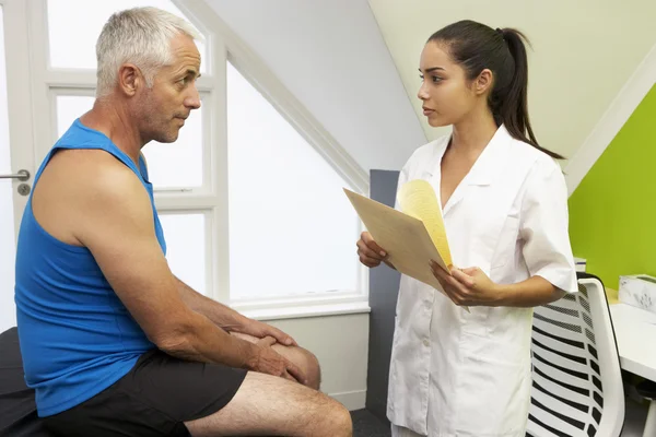 Fisioterapeuta deportivo que trata al cliente masculino — Foto de Stock