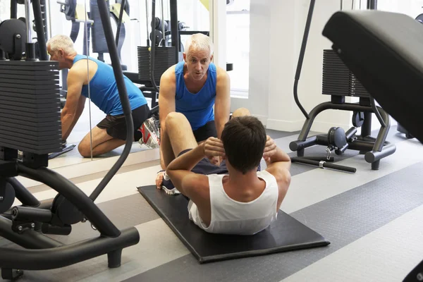 Mann arbeitet mit Personal Trainer im Fitnessstudio — Stockfoto