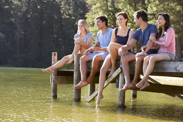 Grupa przyjaciół, siedząc na drewniane molo — Zdjęcie stockowe