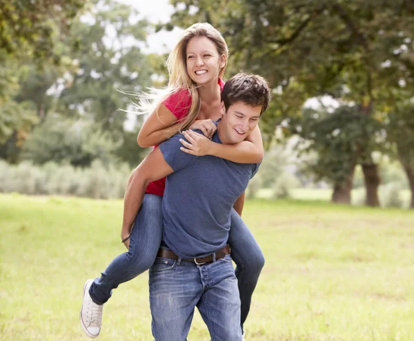 Człowiek daje kobieta piggyback — Zdjęcie stockowe