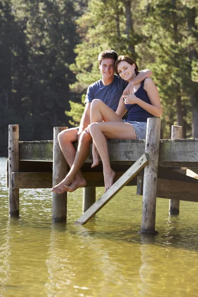 Pareja romántica sentada en jetty de madera — Foto de Stock
