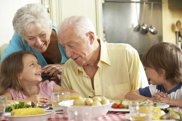 Abuelos y nietos comiendo comida en la cocina — Foto de Stock