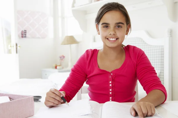 Chica joven haciendo la tarea en el escritorio — Foto de Stock