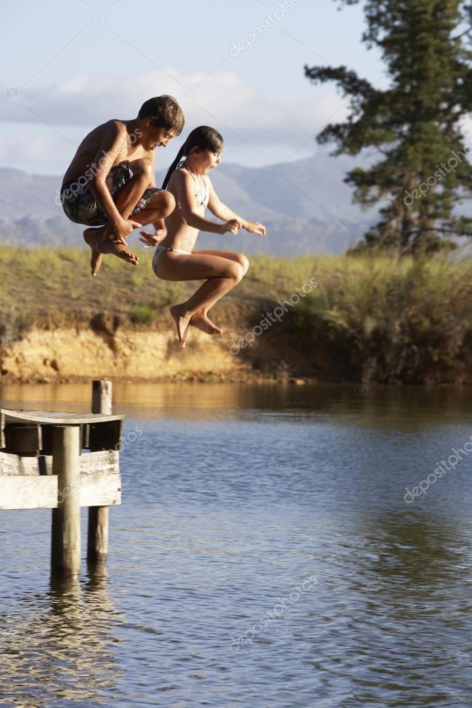 Children Jumping From Jetty Into Lake — Stock Photo © monkeybusiness