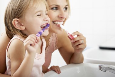 Mother And Daughter Brushing Teeth clipart