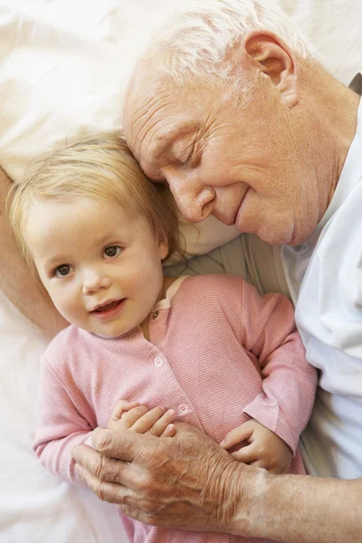 Abuelo acurrucado nieta en la cama —  Fotos de Stock