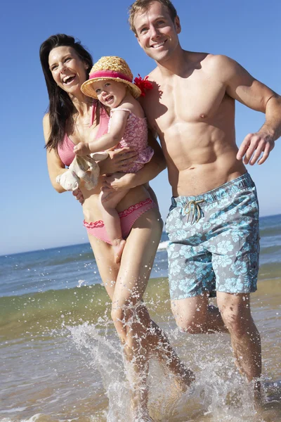 Famiglia con figlia che corre lungo la spiaggia — Foto Stock