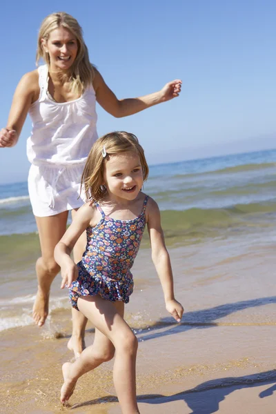 Mamma jagar dotter längs stranden — Stockfoto