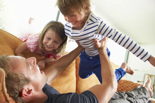 Ojciec i dzieci leżąc na kanapie w domu — Zdjęcie stockowe
