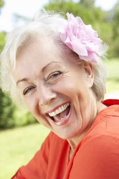 Femme âgée souriante avec fleur — Photo