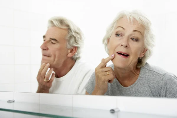 Pareja mayor mirando reflexiones en espejo — Foto de Stock