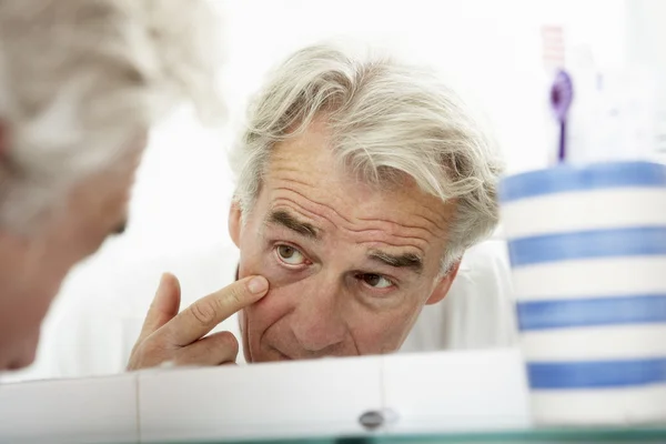Втомився старший чоловік дивиться в дзеркало — стокове фото