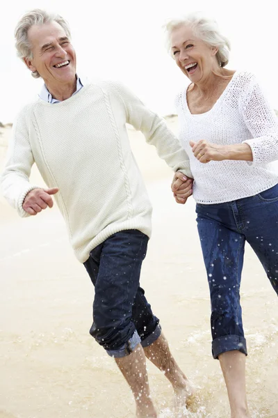 Seniorenpaar läuft am Strand entlang — Stockfoto