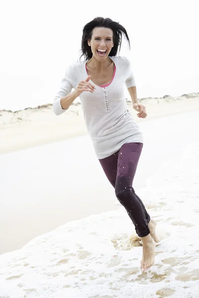 Жінка біжить уздовж пляжу — стокове фото