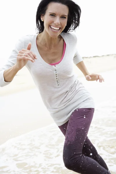 Mulher correndo ao longo da praia — Fotografia de Stock