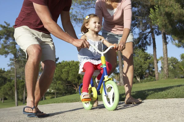 Padres enseñando a la hija a andar en bicicleta — Foto de Stock