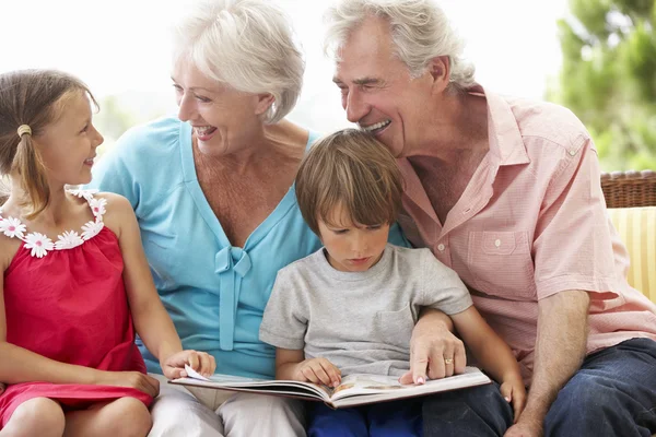 Großeltern und Enkel lesen Buch — Stockfoto