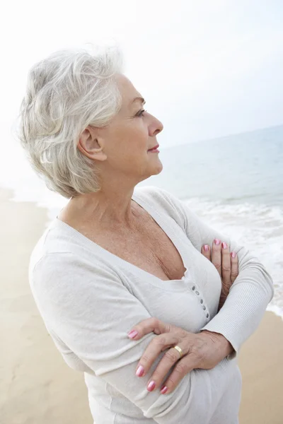 Mujer mayor reflexiva de pie en la playa — Foto de Stock