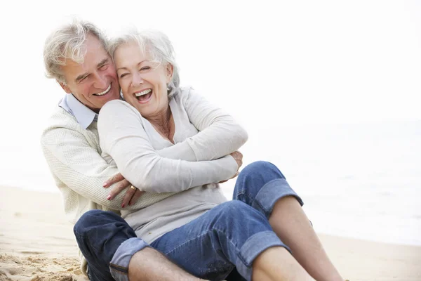 Старшая пара сидит на пляже — стоковое фото