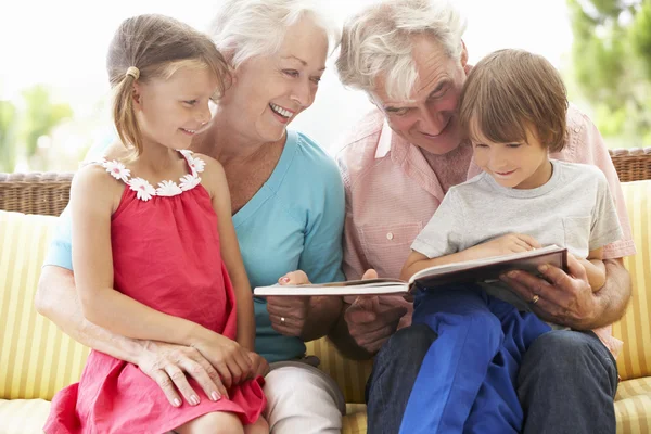 Far-och morföräldrar och barnbarn läser bok — Stockfoto