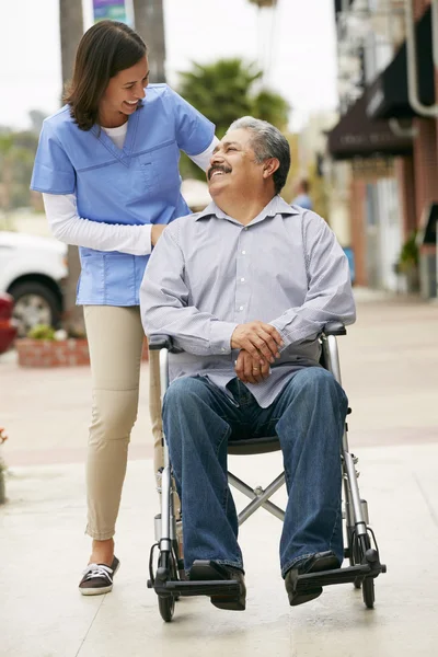 Carer spingendo uomo anziano in sedia a rotelle — Foto Stock