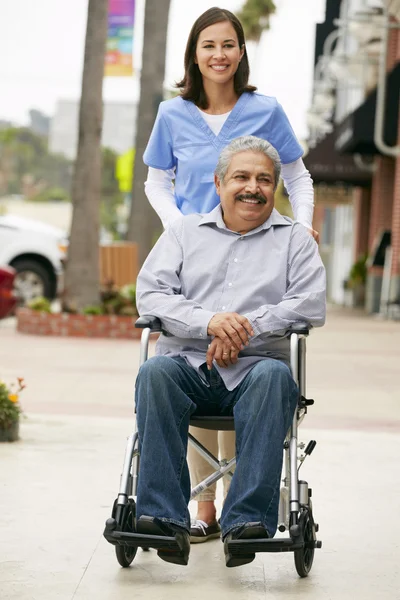 Verzorger duwen senior man in rolstoel — Stockfoto